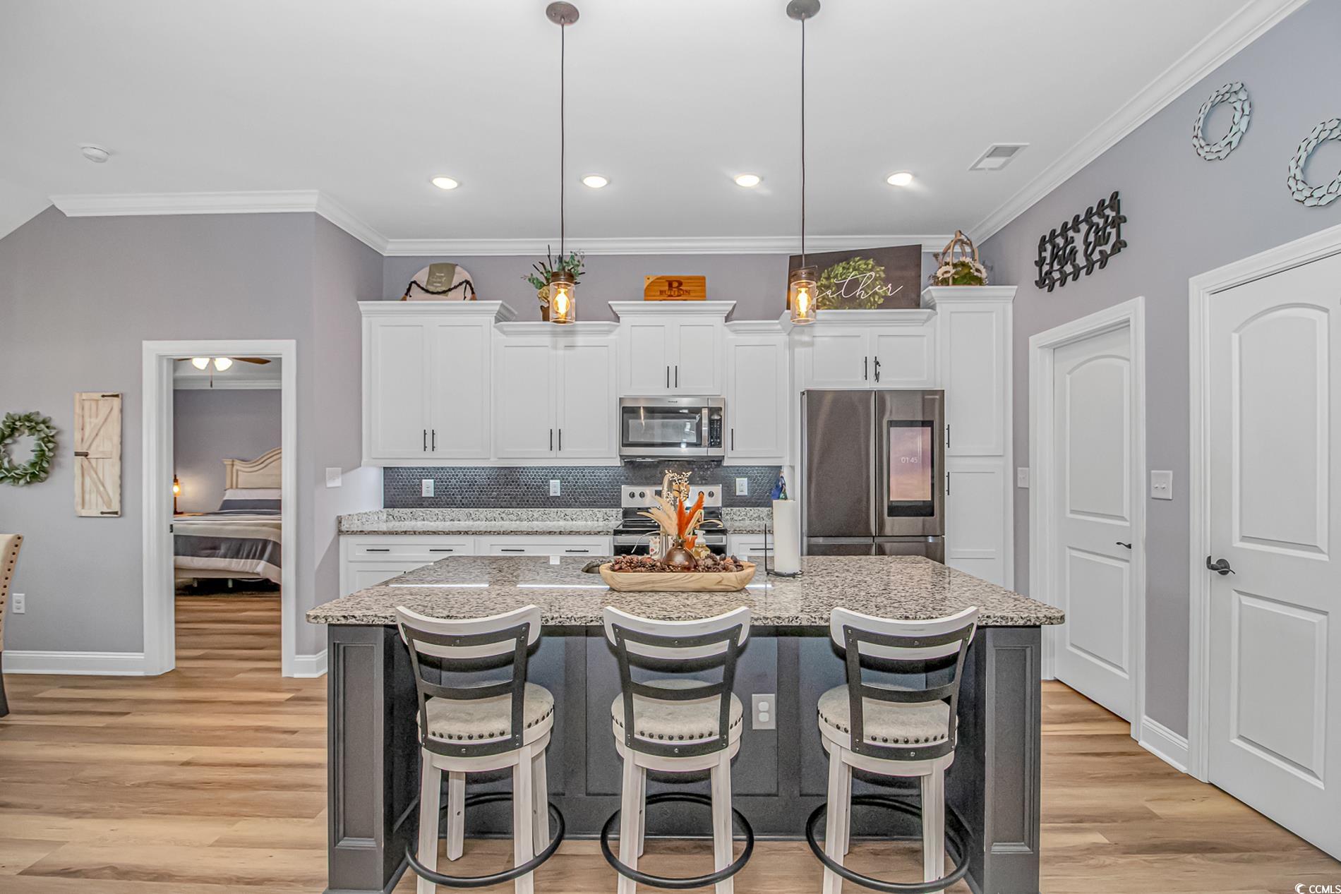 4082 Edwards Road Aynor, SC 29511 - Photo 9 of 40 Kitchen with a kitchen breakfast bar, backsplash, a kitchen island with sink, appliances with stainless steel finishes, and white cabinetry