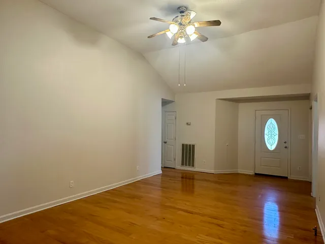 a view of an empty room with wooden floor and a window