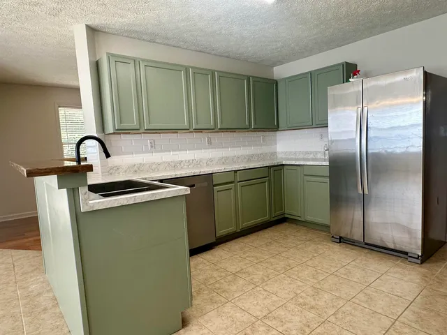 a kitchen with kitchen island a sink a counter and a refrigerator