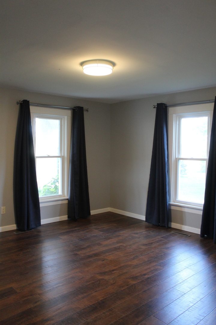 7496 Wolf Road Kingston, IL 60145 - Photo 8 of 38 an empty room with wooden floor and windows