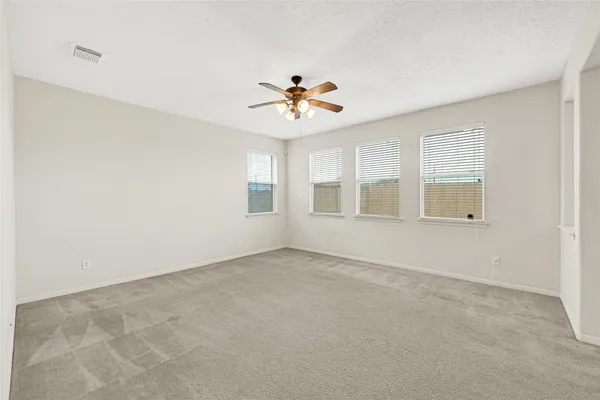 an empty room with chandelier fan and windows