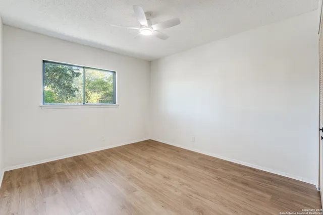 an empty room with a window and a ceiling fan