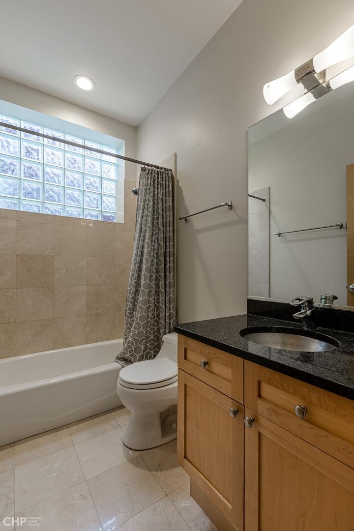 1050 North Hermitage Avenue, Unit 1 Chicago, IL 60622 - Photo 14 of 18 a bathroom with a granite countertop sink a toilet a mirror and bathtub