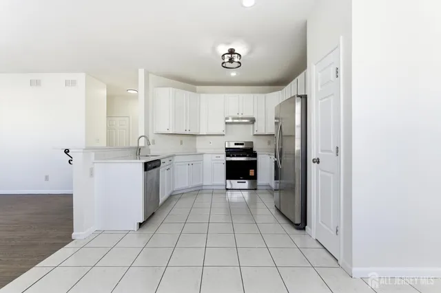 a kitchen with a stove a refrigerator and white cabinets
