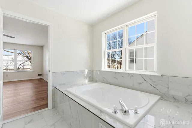 a white bath tub sitting in a bathroom next to a window
