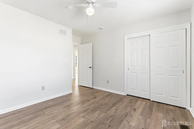 an empty room with wooden floor and fan