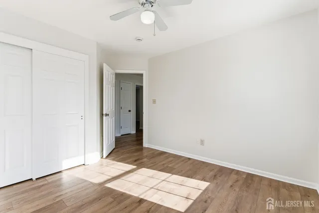 an empty room with wooden floor and fan