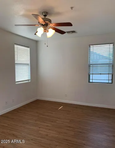 a view of a room with wooden floor fan and windows