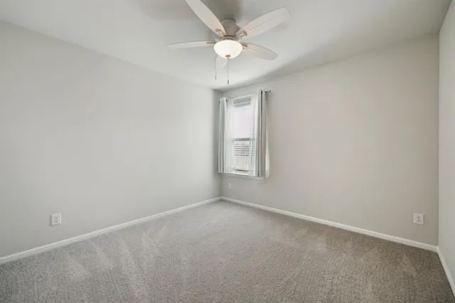 an empty room with a window and a fan