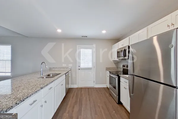a kitchen with stainless steel appliances granite countertop a refrigerator a sink a stove and a wooden floors