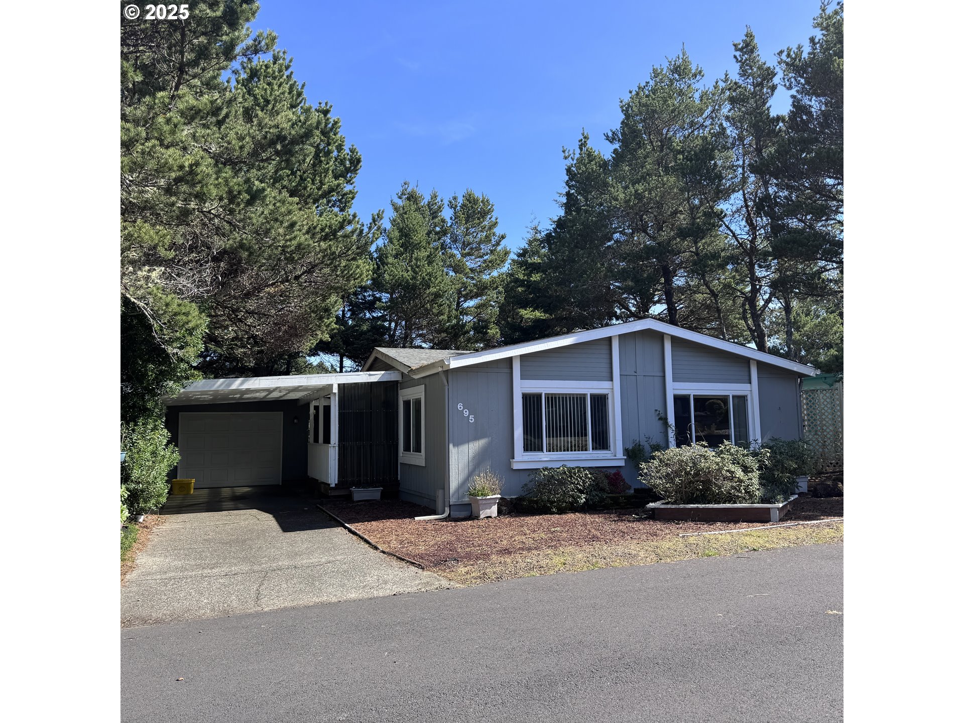 1601 Rhododendron Drive, Unit 695 Florence, OR 97439 - Photo 1 of 42 a front view of a house with a yard and garage