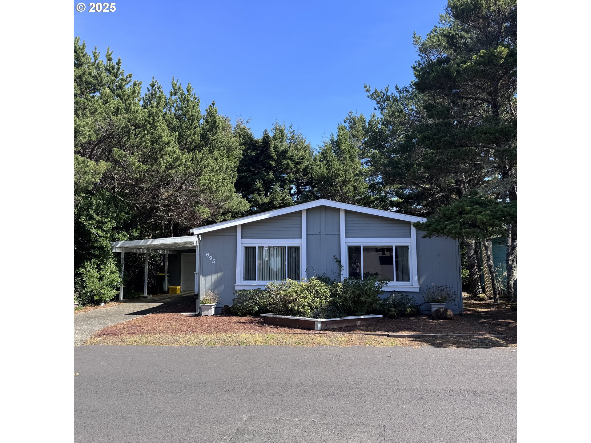 1601 Rhododendron Drive, Unit 695 Florence, OR 97439 - Photo 2 of 42 a front view of a house with a yard and trees