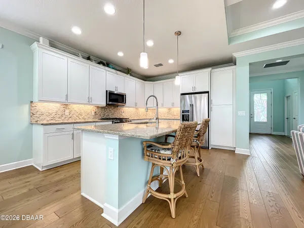 a kitchen with stainless steel appliances granite countertop a stove top oven a refrigerator a sink and a dining table with wooden floor