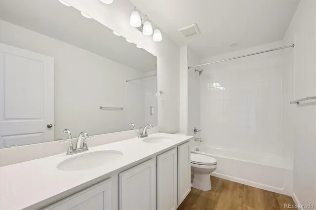 a bathroom with a double vanity sink toilet mirror and bathtub