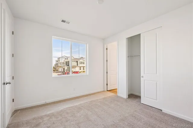 a view of an empty room with window and closet area