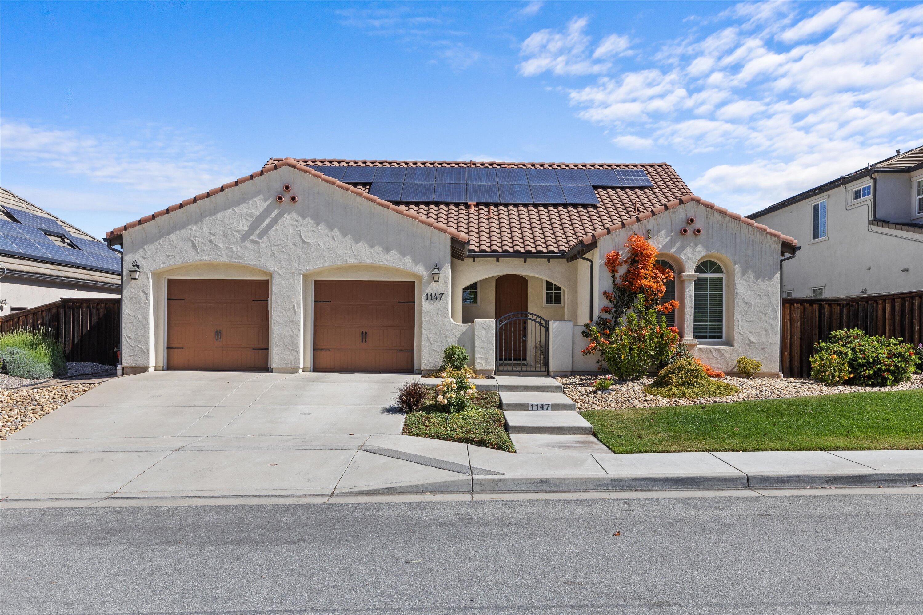 a front view of a house with a garden and mountain