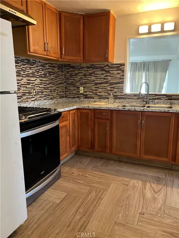 a view of a livingroom with wooden floor and a refrigerator
