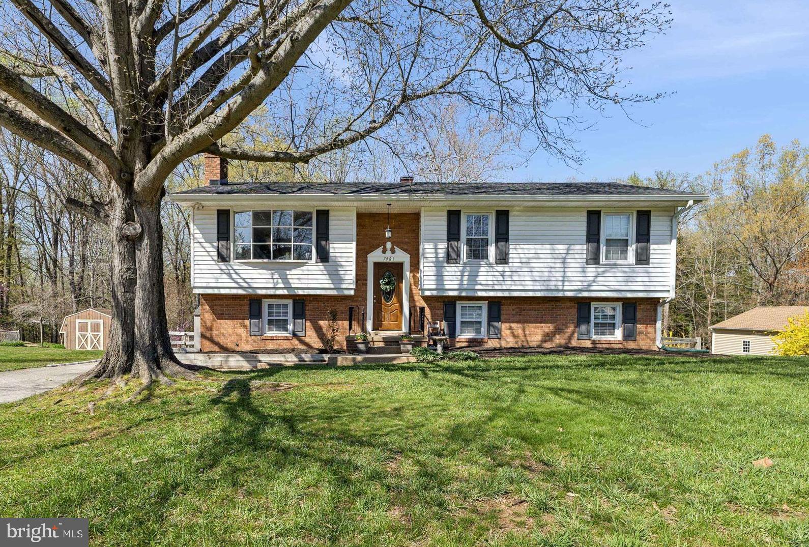 a view of a brick house with a yard and large trees