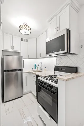 a kitchen with cabinets stainless steel appliances and a counter space