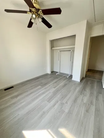 a view of an empty room with a ceiling fan and window