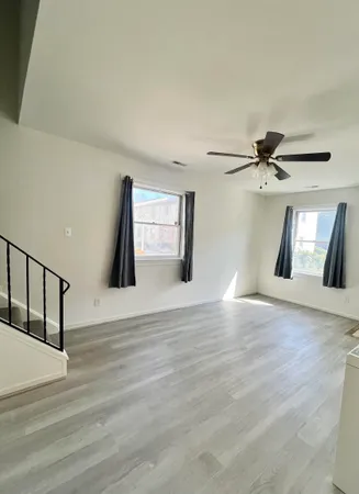 a view of empty room with wooden floor and fan