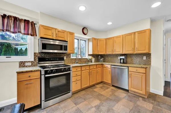 a kitchen with stainless steel appliances granite countertop a stove top oven a sink dishwasher and a microwave oven with cabinets