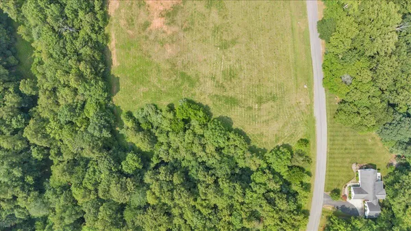 an aerial view of a houses with a yard and lake view