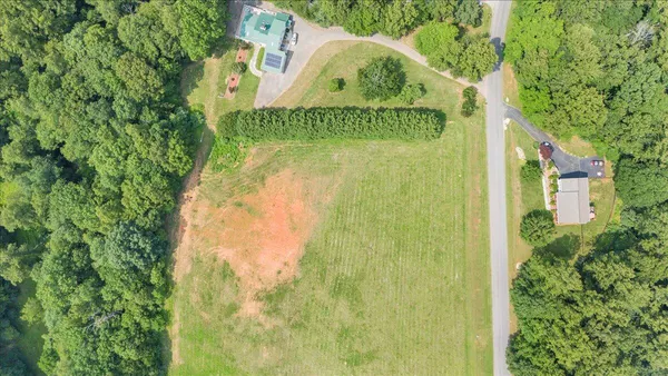 an aerial view of a residential houses with outdoor space and trees