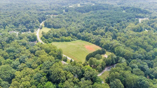 an aerial view of residential houses with outdoor space and trees all around
