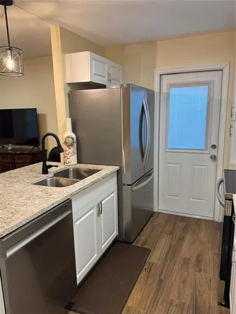 a kitchen with stainless steel appliances granite countertop a refrigerator a sink and a stove with wooden floors