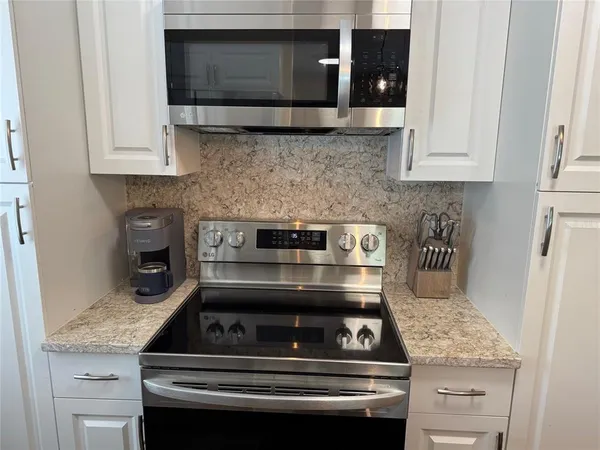 a kitchen with granite countertop a stove and a microwave