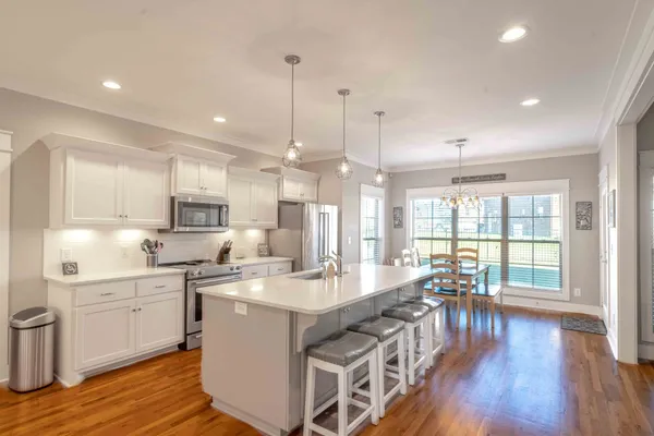 a kitchen with stainless steel appliances granite countertop a stove a sink a refrigerator a center island with wooden floor and cabinets