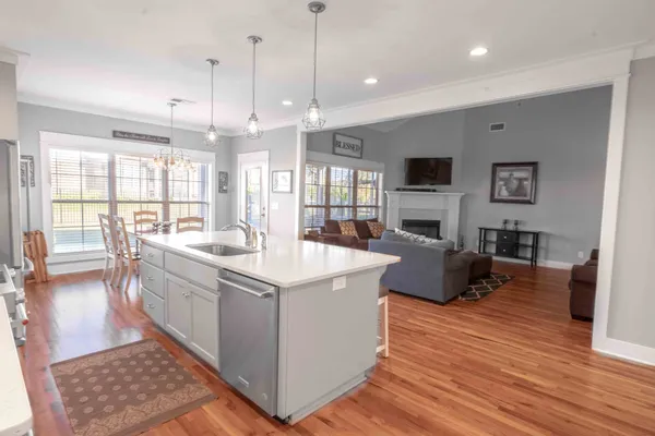 a large kitchen with stainless steel appliances kitchen island granite countertop a large stove a sink a dining table and chairs with wooden floor