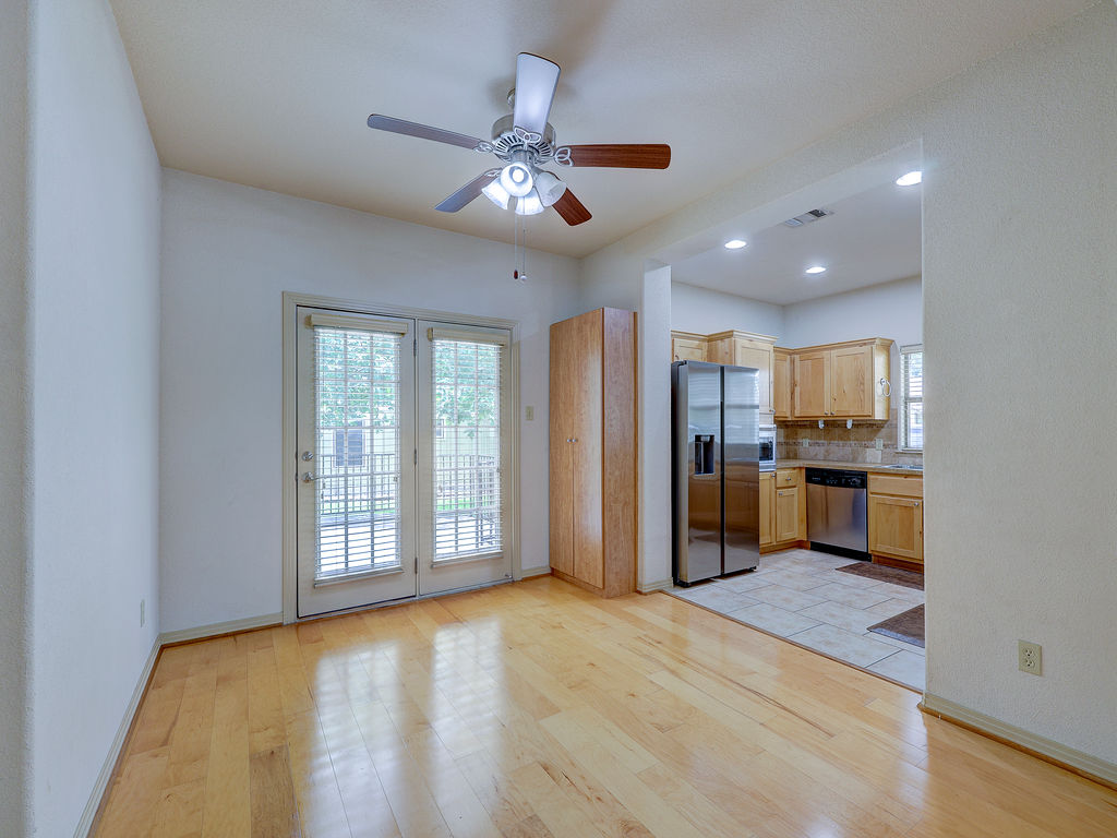 9707 Anderson Mill Road, Unit 22 Austin, TX 78750 - Photo 27 of 39 Hardwood flooring extends throughout this well-lit space, offering a view into the kitchen and beyond through elegant French doors.