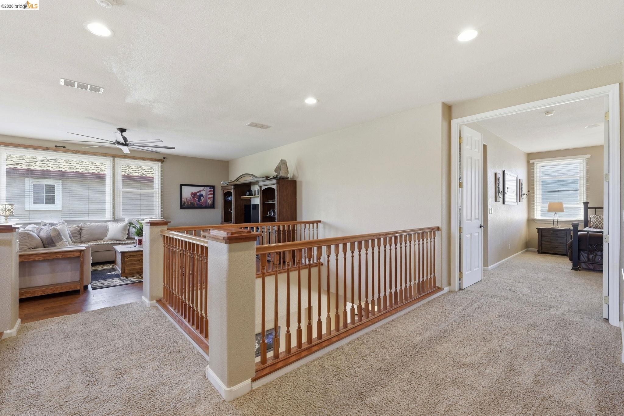 3438 Keystone Loop Discovery Bay, CA 94505 - Photo 18 of 57 Carpeted landing featuring a wooden banister overlooking a living area with wood-finish flooring