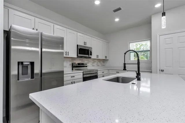 a kitchen with a refrigerator a sink a stove and cabinets