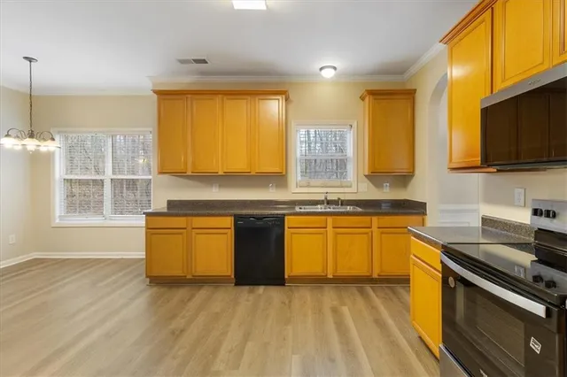 a kitchen with stainless steel appliances granite countertop a sink a stove top oven a counter space and cabinets