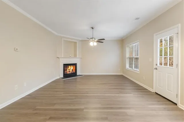 a view of an empty room with wooden floor fireplace and a window