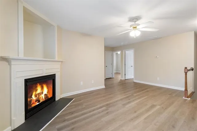 a view of an empty room with wooden floor and fireplace