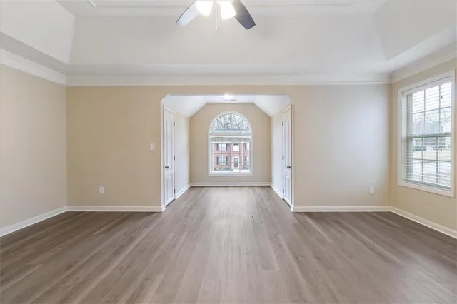 an empty room with wooden floor cabinet and windows