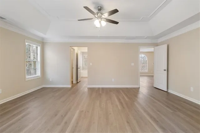 an empty room with wooden floor and a ceiling fan