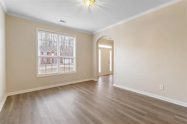 an empty room with wooden floor and windows