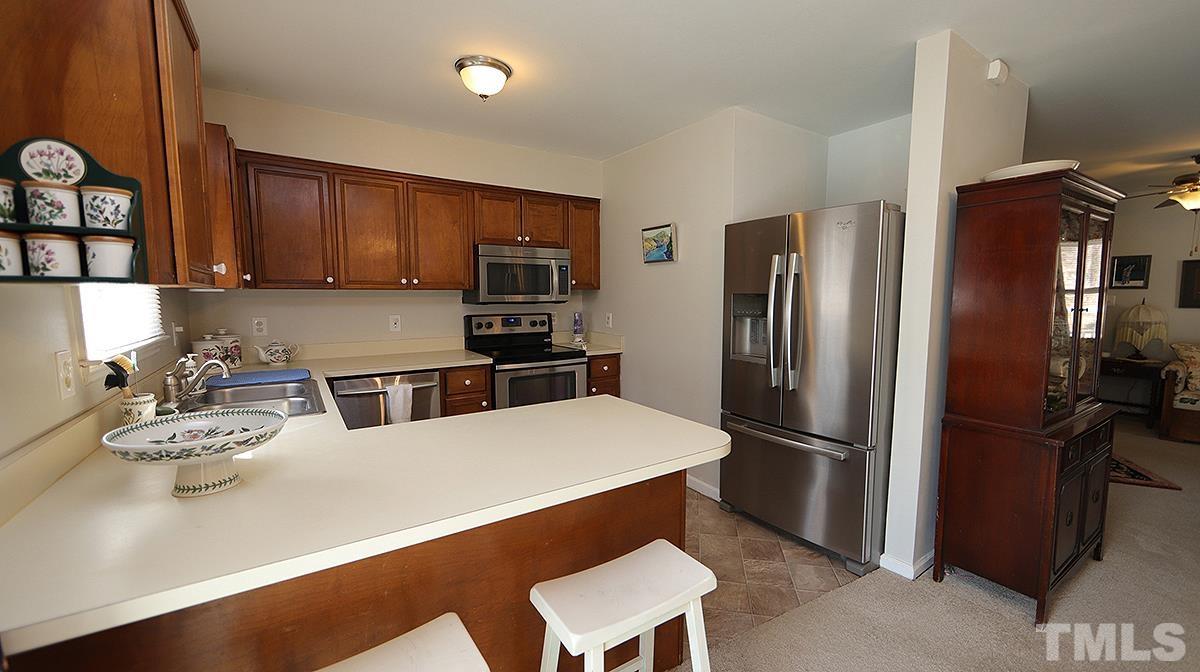 10633 Old Stage Road Raleigh, NC 27603 - Photo 8 of 20 a kitchen with stainless steel appliances granite countertop a refrigerator a stove a sink a dining table and chairs with wooden floor