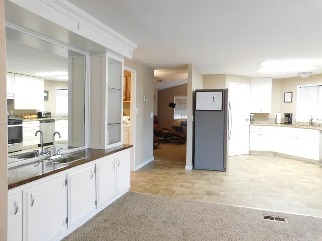 a large white kitchen with a sink and refrigerator
