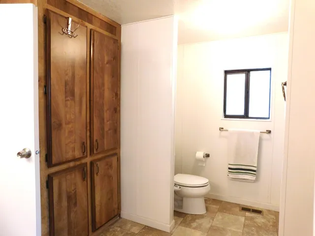 a bathroom with a toilet a window and shower