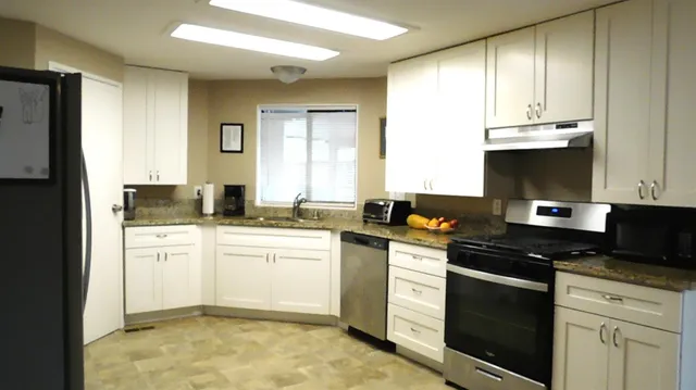 a kitchen with granite countertop white cabinets and stainless steel appliances