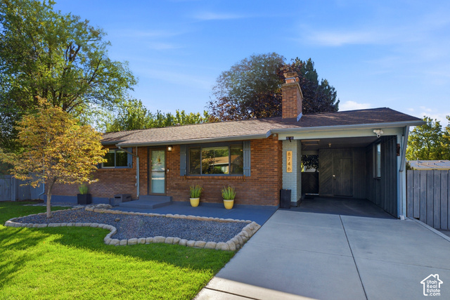8746 Gladiator Way Sandy, UT 84094 - Photo 35 of 36 Brick exterior with a covered carport, concrete driveway, and landscaped front yard featuring a gravel bed