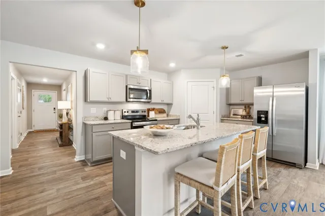 a kitchen with stainless steel appliances granite countertop a sink a stove a refrigerator cabinets and chairs