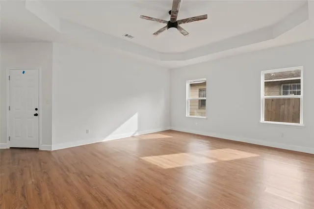 a view of an empty room with wooden floor and a window