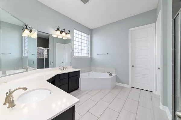 a spacious bathroom with a tub sink and mirror